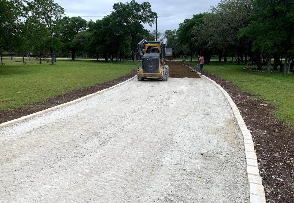 Compact skid steer grading rural driveway in West Texas
