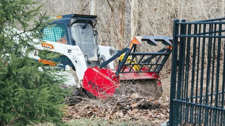 Compact skid steer cleaning fence line in West Texas